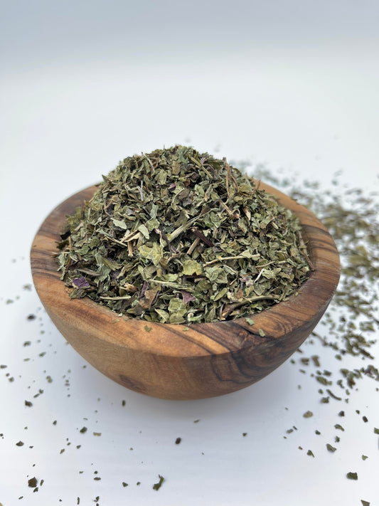 Wooden bowl filled with dried Lemon Balm herbs - promotes relaxation, boosts immunity, aids digestion, and enhances cognitive function.